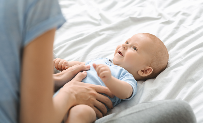 Matka wykonuje masaż brzucha na kolkę u niemowlaka