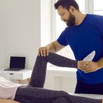 Fizjoterapeuta wykonuje terapię manualną na pacjentce z zapaleniem ścięgna achillesa