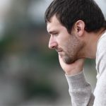 zmartwiony mężczyzna patrzy przed siebie, cierpi na depresję reaktywną (nerwicową)