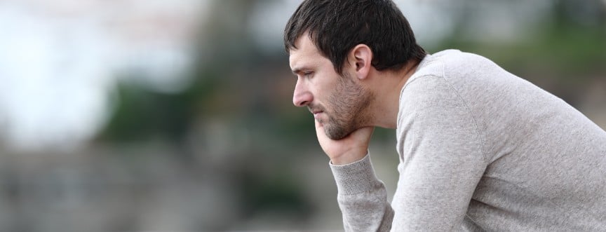 zmartwiony mężczyzna patrzy przed siebie, cierpi na depresję reaktywną (nerwicową)