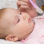 rodzic podaje niemowlakowi syrop na kaszel