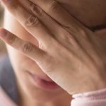 młoda kobieta zasłania twarz dłonią, ma objawy PMDD