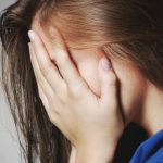 młoda kobieta cierpiąca na bulimię chowa twarz w dłoniach