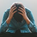 mężczyzna podtrzymuje głowę rękami, ma ostrą reakcję na stres