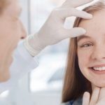 nastolatka podczas wizyty u dermatologa, który ogląda jej skórę twarzy