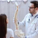 lekarz pokazuje pacjentce model kręgosłupa i tłumaczy, jak dbać o zdrowy kręgosłup