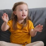 dziewczynka z zespołem Downa siedzi na kanapie