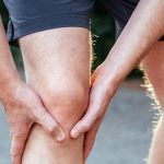 Mężczyzna trzymający się za kolano z powodu zapalenia kaletki maziowej
