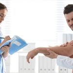 Lekarka bada mężczyznę, który cierpi na zespół ciasnoty podbarkowej