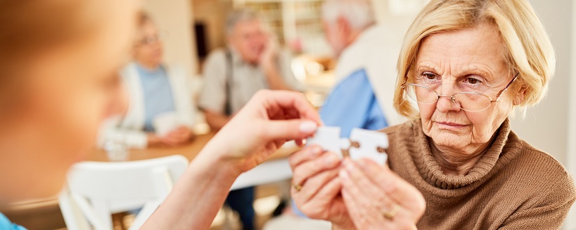 Starsza kobieta trzymająca puzzle w rękach - ćwiczenia wykonywane w chorobie Alzheimera