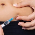Kobieta prezentująca co to jest iniekcja podskórna - wprowadza lek w fałd skórny na brzuchu