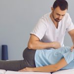 Osteopata wykonuje manipulacje kręgosłupa u pacjentki leżącej na stole do masażu