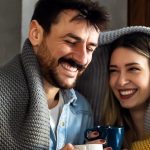 Kobieta i mężczyzna okryci kocem, piją herbatę na przeziębienie