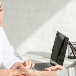 Dermatolog ogląda przebarwienia na paznokciach u pacjentki