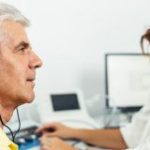 Mężczyzna ze słuchawkami na uszach podczas badania słuchu u laryngologa