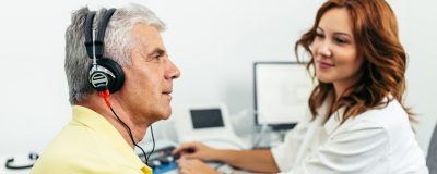 Mężczyzna ze słuchawkami na uszach podczas badania słuchu u laryngologa