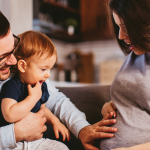 Tata z dzieckiem trzymają rękę na brzuchu mamy w 3. miesiącu ciąży