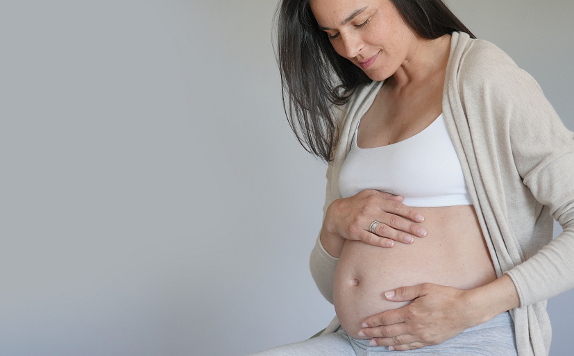 Kobieta pokazuje, jak wygląda brzuch w 6 miesiącu ciąży