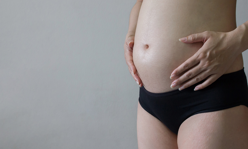 Kobieta pokazuje, jak wygląda brzuch w 5. miesiącu ciąży