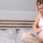 26. tydzień ciąży - kobieta smaruje brzuch ciążowy kremem nawilżającym skórę