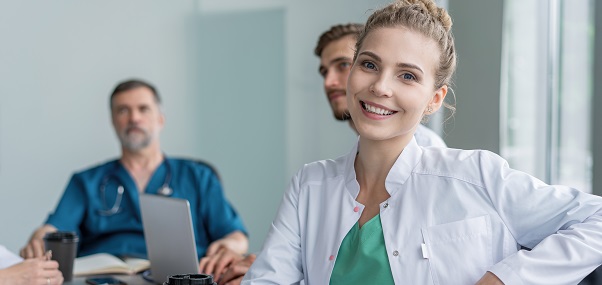 Uśmiechnięta doktorka podczas zebrania z innymi lekarzami