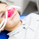 Dziecko z maską do sedacji wziewnej gazem rozweselającym u dentysty