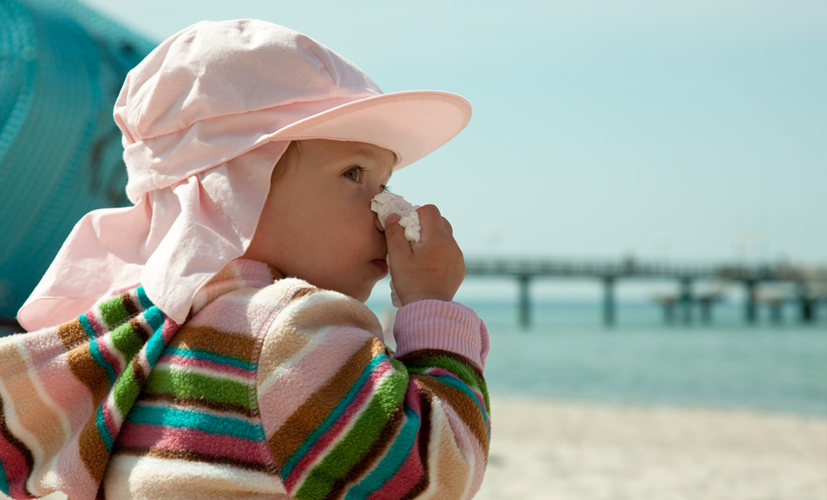 Dziecko wyciera nos na plaży - środki na przeziębienie w apteczce na wyjazd z dzieckiem pomogą zwalczyć objawy