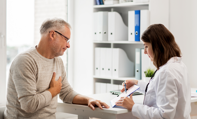 Lekarka pokazuje wyniki badań cholesterolu mężczyźnie z bólami serca - kalkulator cholesterolu pozwala oszacować ryzyko chorób sercowo-naczyniowych