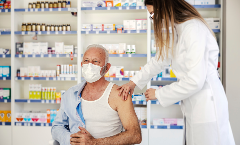Farmaceuta w aptece wykonuje szczepienie mężczyzny 